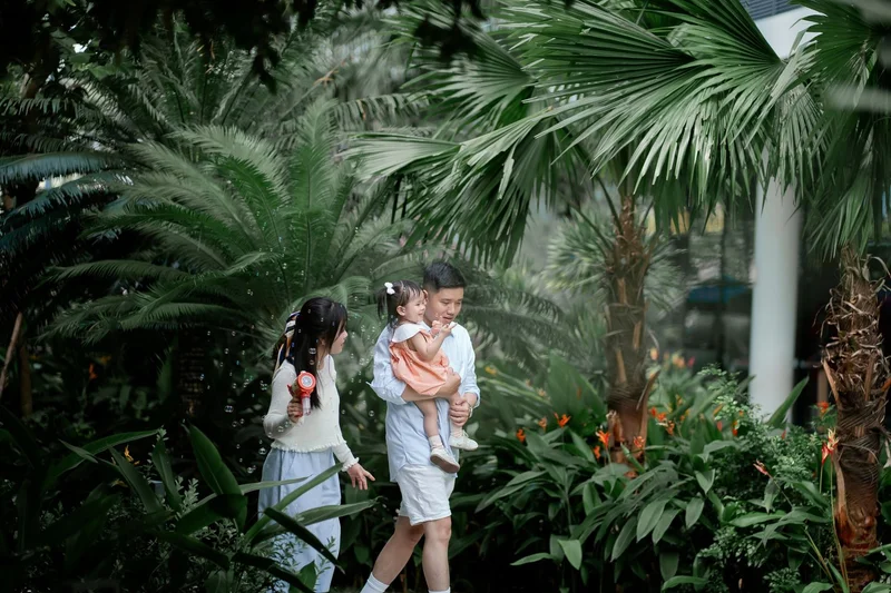 Family with a young child outdoors in a garden, blowing bubbles together